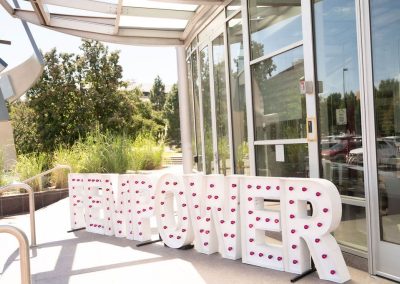 Large white letters spelling "FEMPOWER" with red lights are displayed outside The Cable Center’s glass entrance on a sunny day, creating a unique and elegant touch to this Denver event venue.