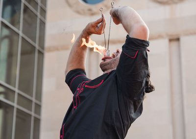 A man wearing a black shirt performs a fire-eating stunt outside during an event at The Cable Center in Denver.